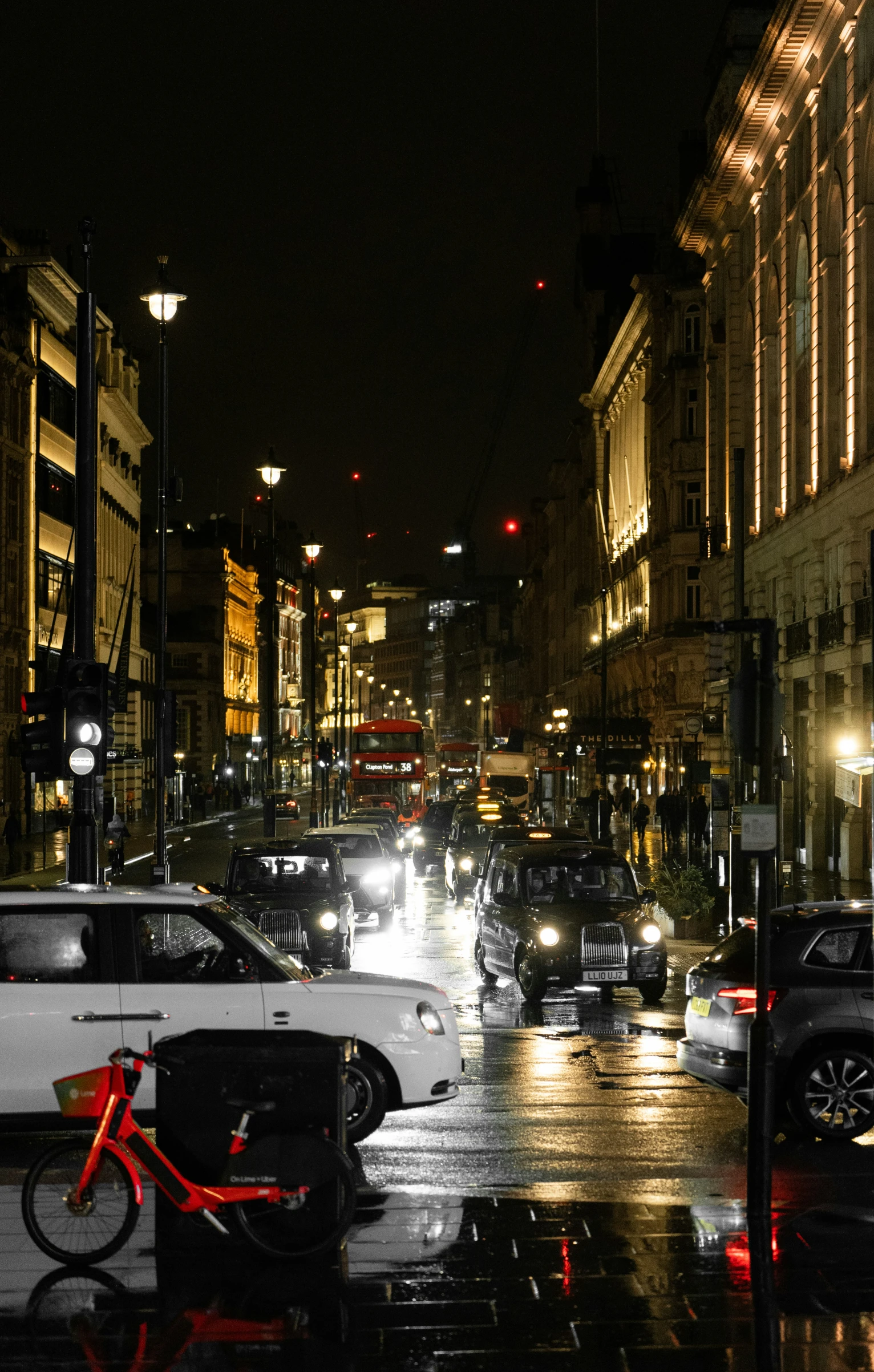 cars and bicycles traveling down a city street at night