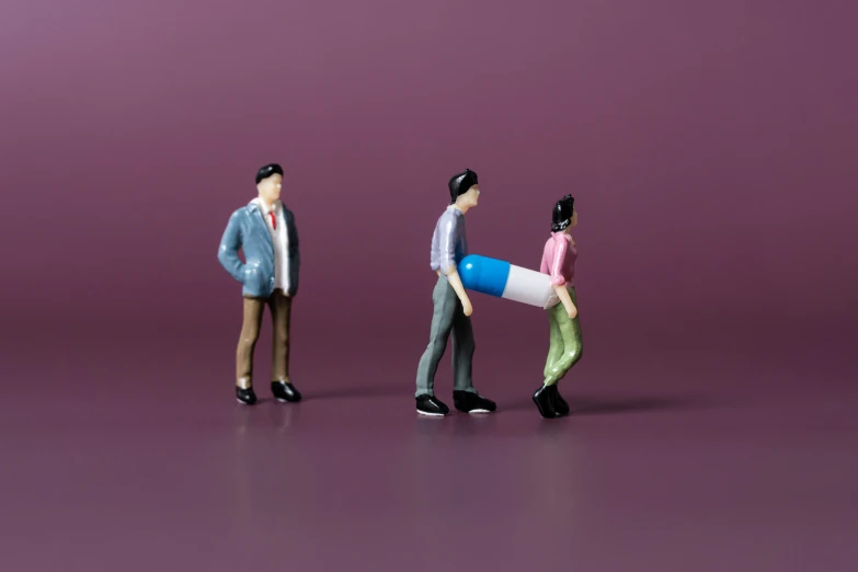 three miniature people walking along a purple background