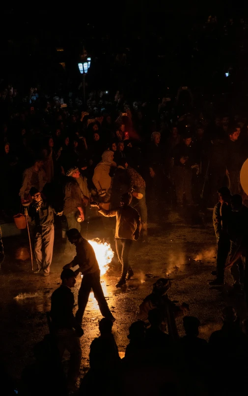 people standing around a large fire and one is holding an umbrella