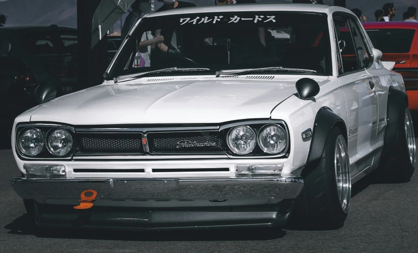 the classic japanese sports car is in a lot with people