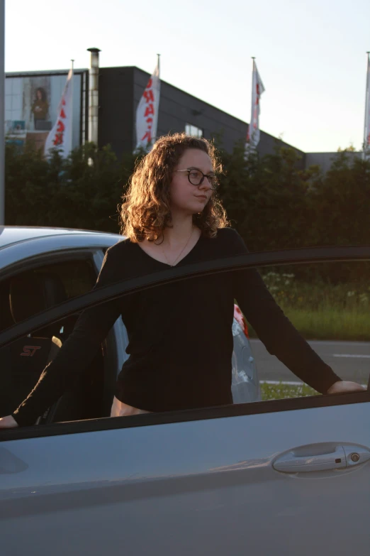 a woman wearing glasses is standing in a car