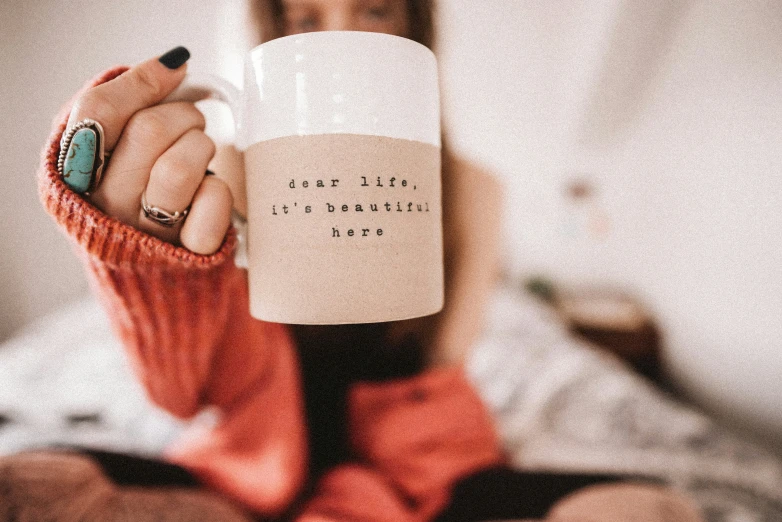 a person is holding a coffee mug with writing on it