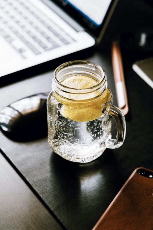 an iphone sitting next to a mug of liquid