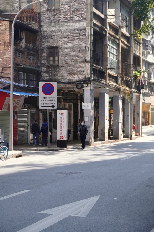 the street in front of the buildings has a sign on the corner and people walking past it