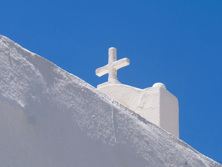 a white cross with snow on it standing above the roof