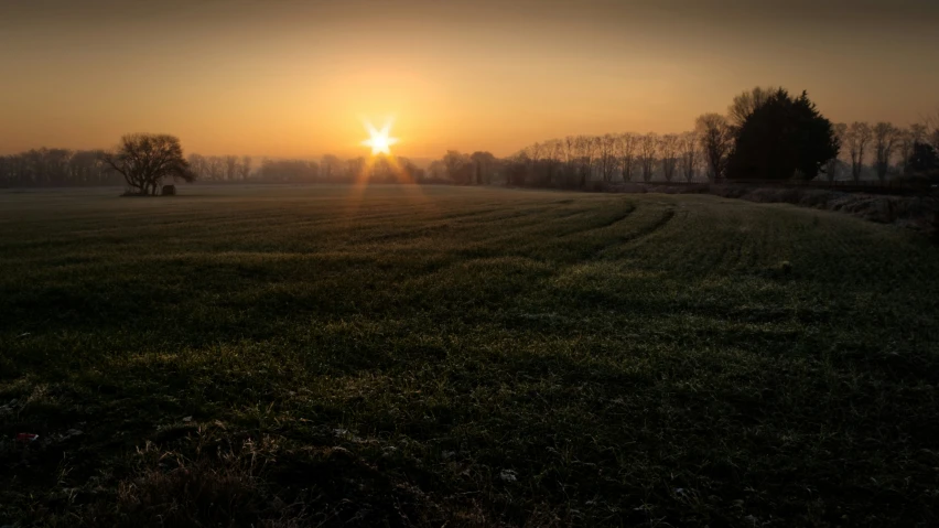 the sun setting over the fields in the countryside