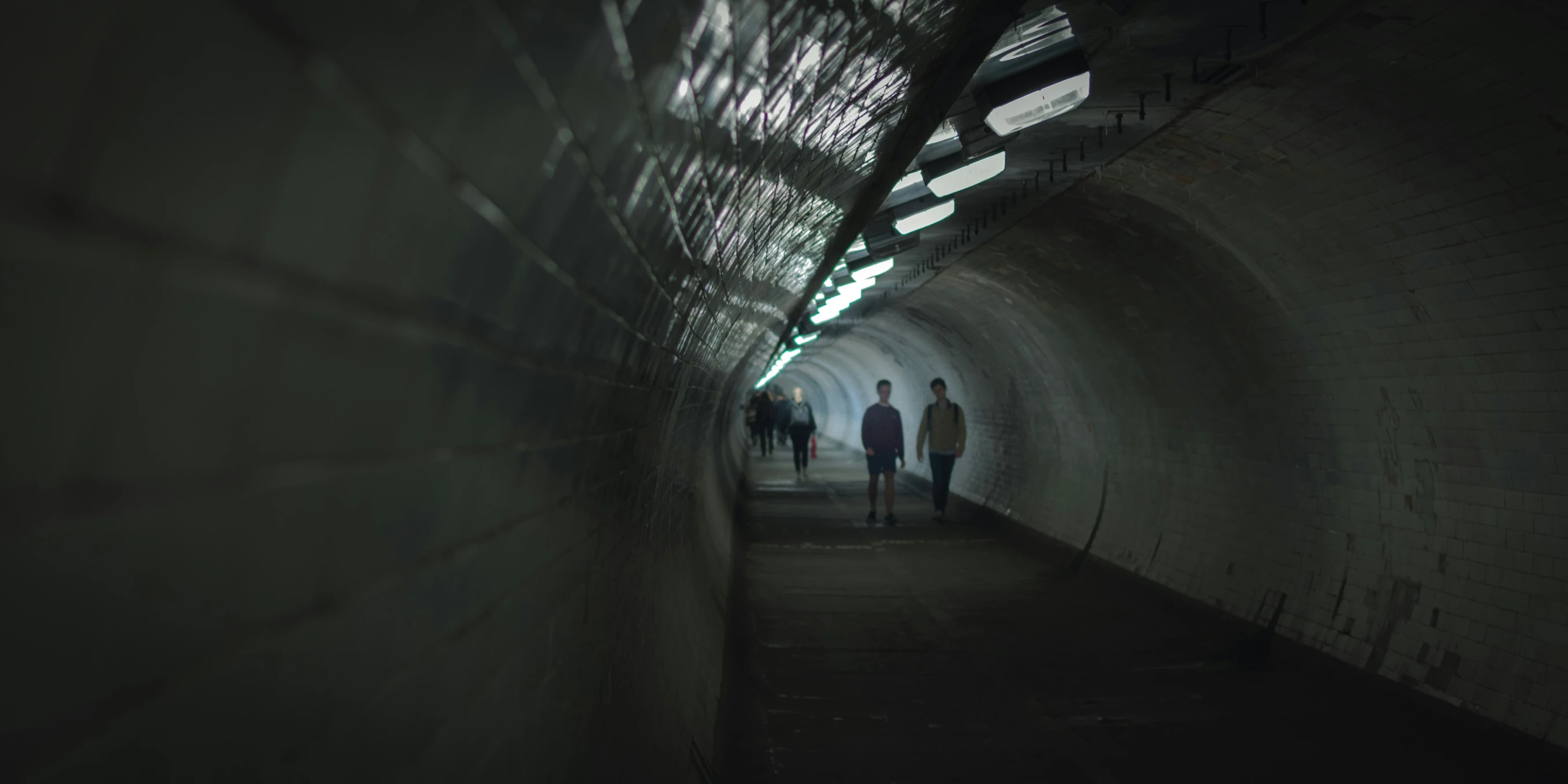 several people are walking in a subway station tunnel