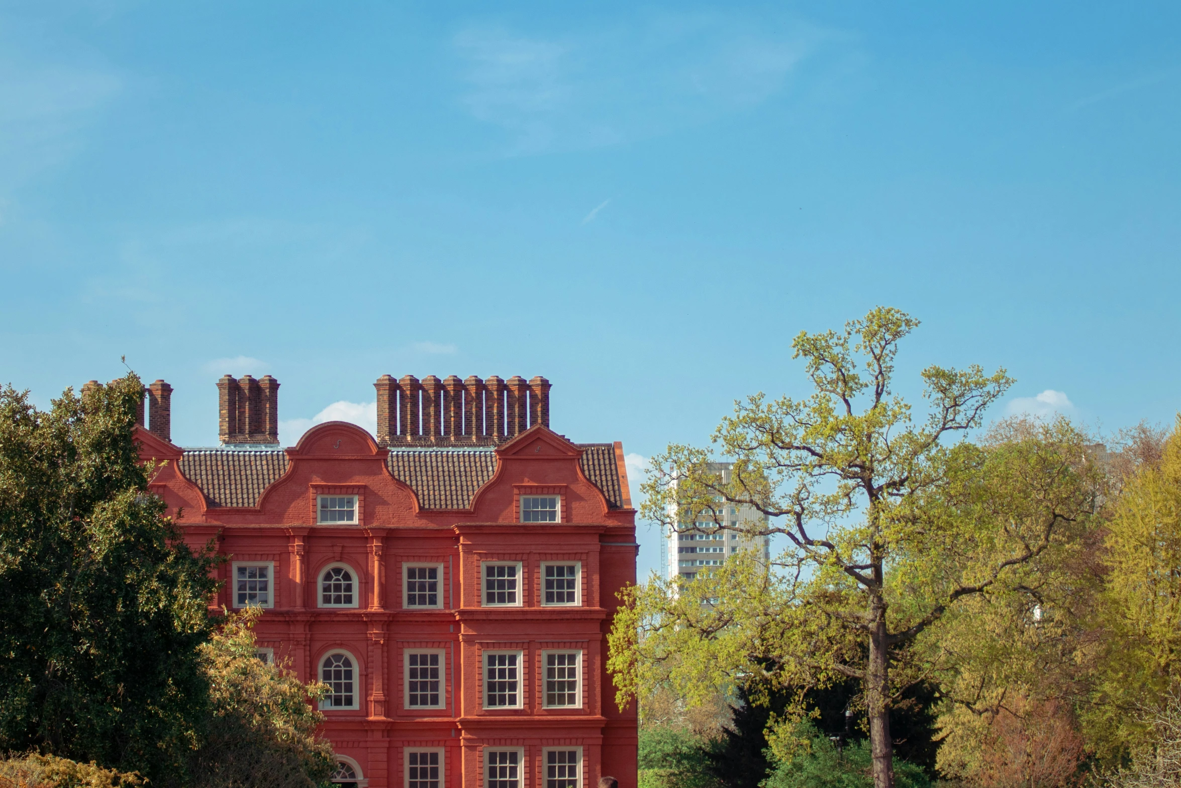 an orange building with many windows is in front of green trees