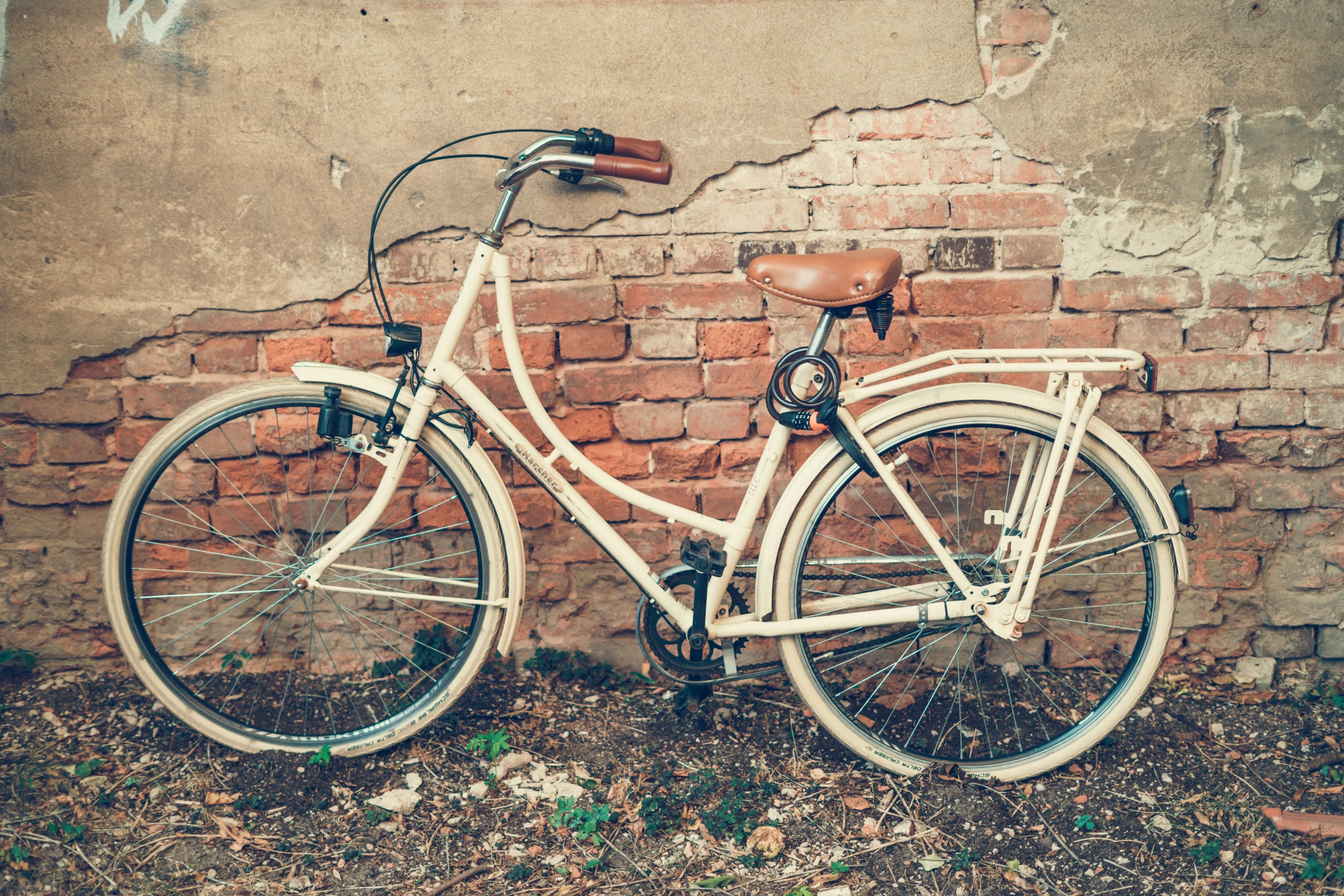 a bicycle parked by a brick wall on the street