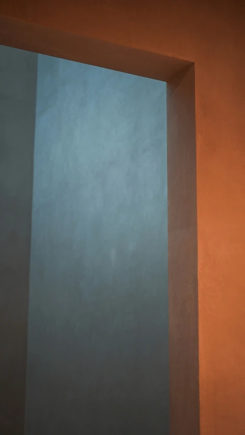 a toilet sits against an orange wall and blue wall