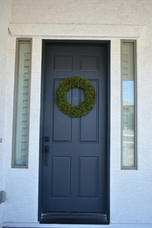 a wreath and two windows in front of a white wall