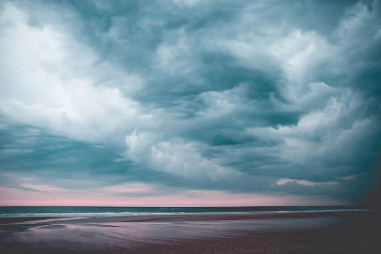 a lone sailboat in the ocean under storm clouds