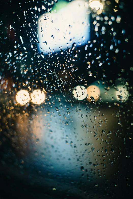 drops of rain on the window and dashboard as the street light passes by