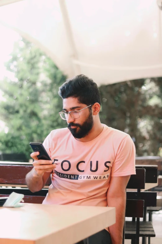 a man sitting at an outside table looking at his phone