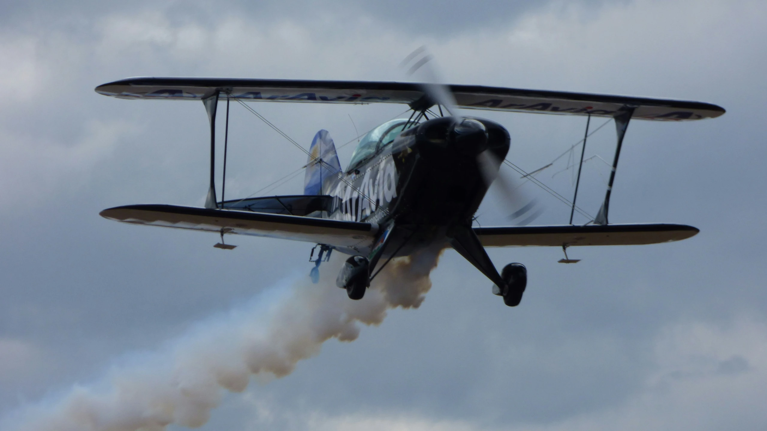 an old airplane flying in the air with smoke coming from it