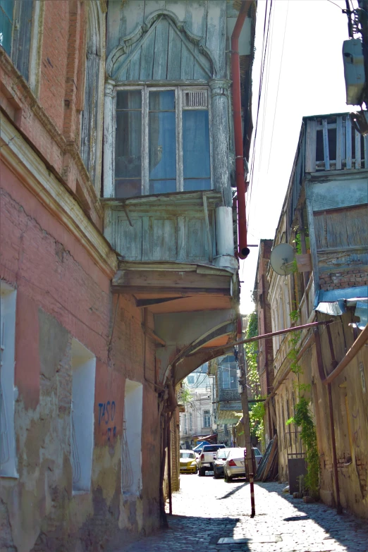 this is an alley between two buildings with a car going down the road