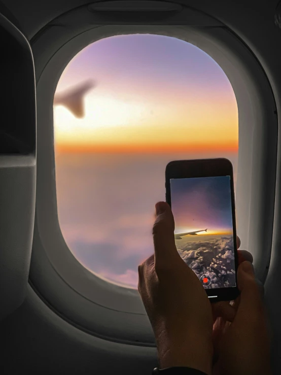 someone's hand holding their phone while flying in an airplane