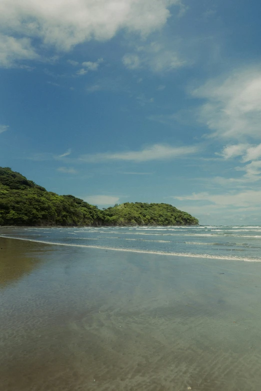 the water at the end of a beach next to a small island