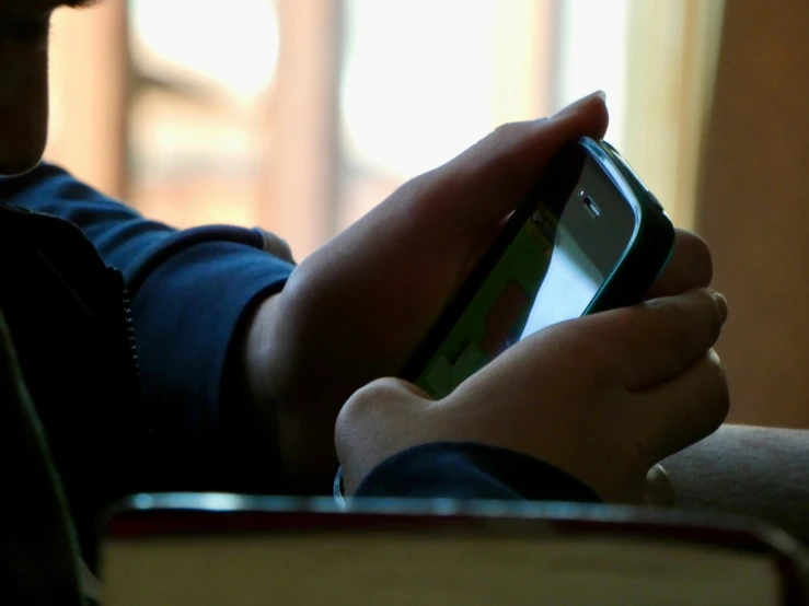 a man holding up a cell phone at his fingertips