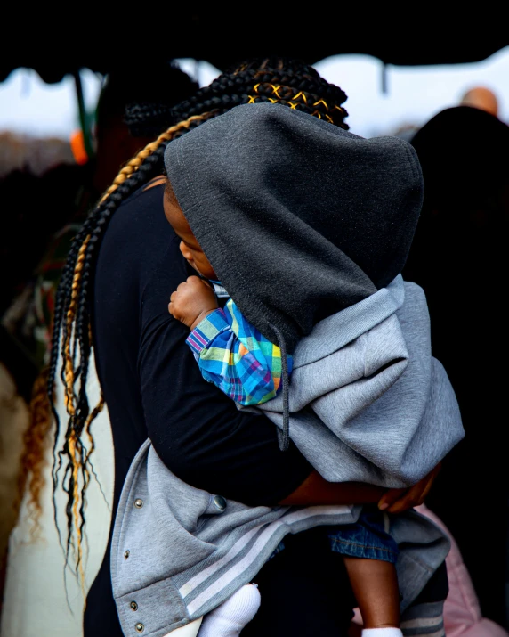 the woman with the child in her sling is looking at their surroundings