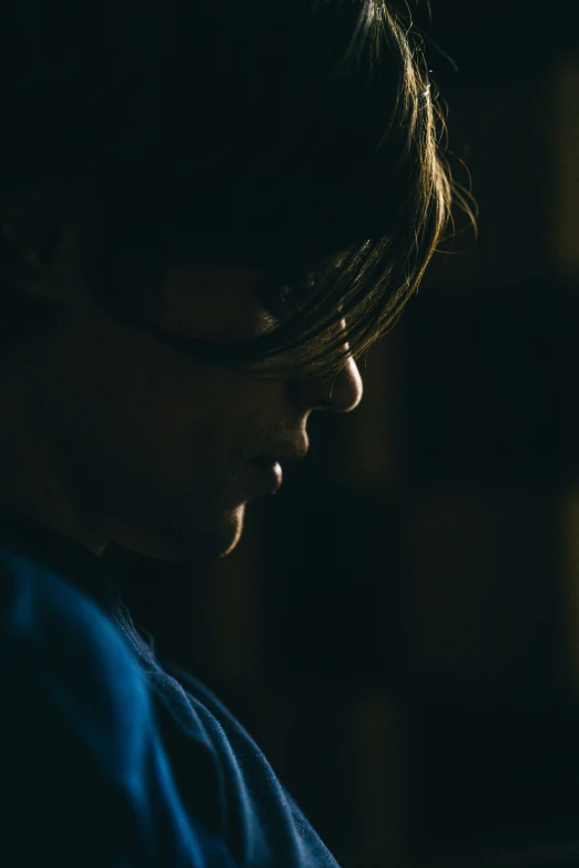 a dark side view of a person wearing glasses in the dark