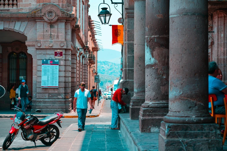 people walking past an ornate building and motorcycles on the street