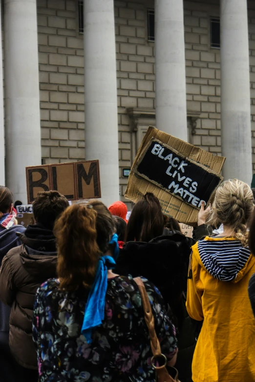 a group of people standing outside with some holding signs