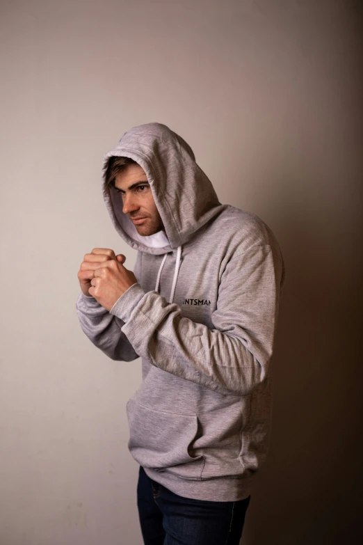 a man in a hoodie stands in front of a wall