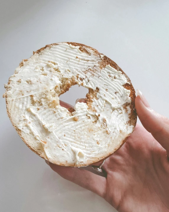 a hand is holding a partially eaten bagel