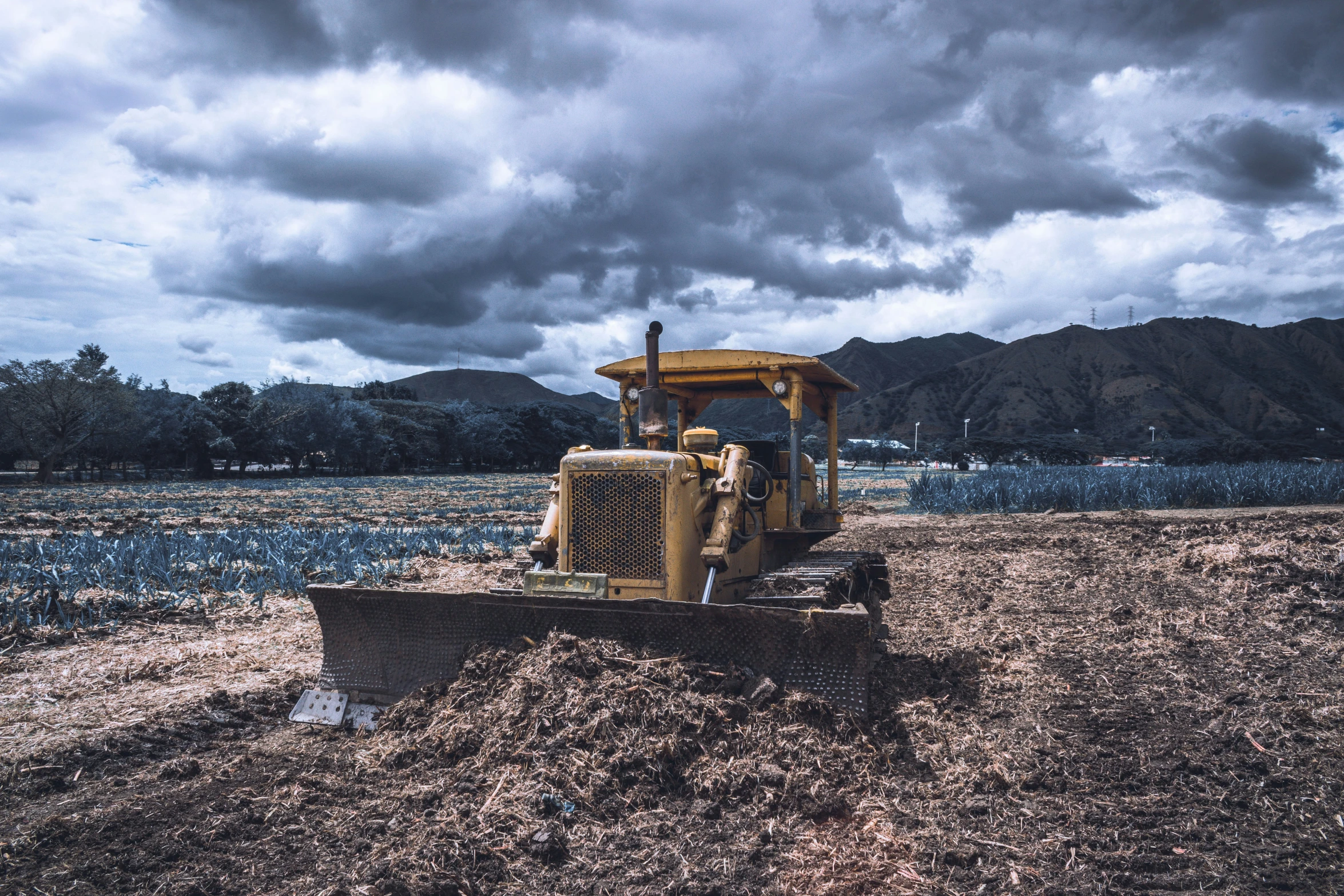 a bulldozer is dumping dirt in a large field