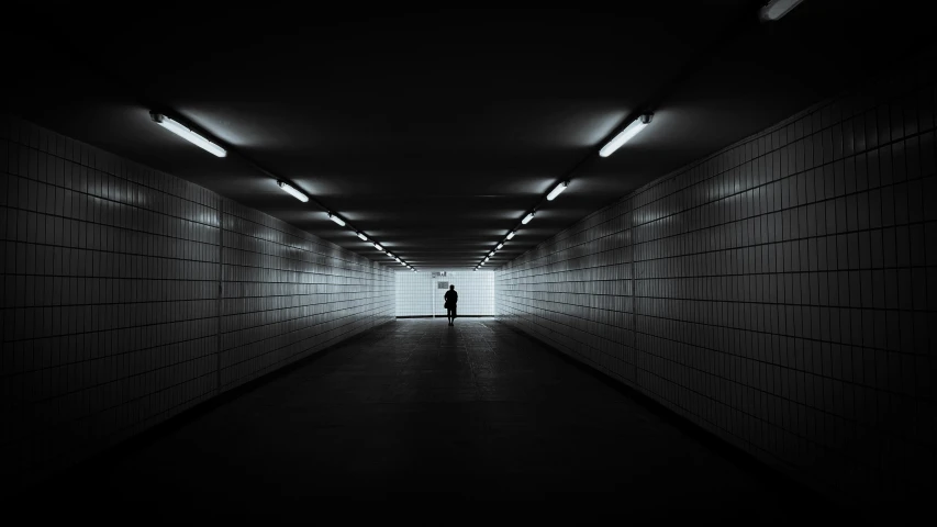 a man standing alone in a dark tunnel