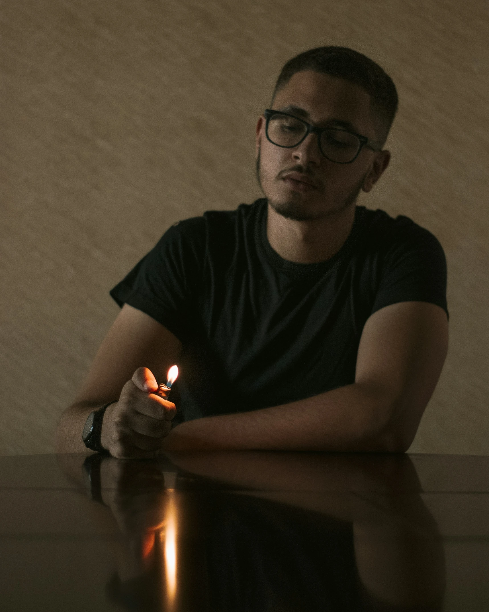 a man with glasses holding a small lit candle