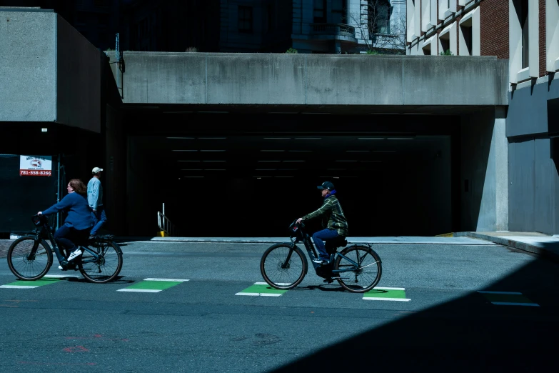 two people on bikes passing under a bridge