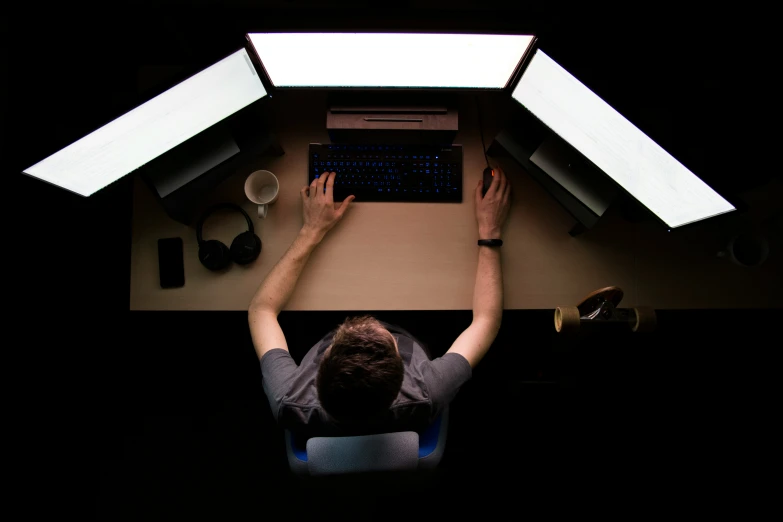 a person sits at a table typing on a laptop