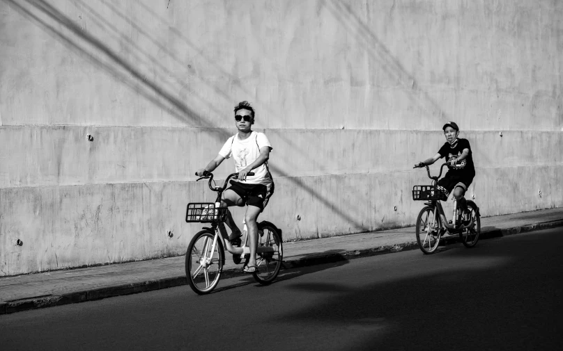 two people ride bicycles down a city street