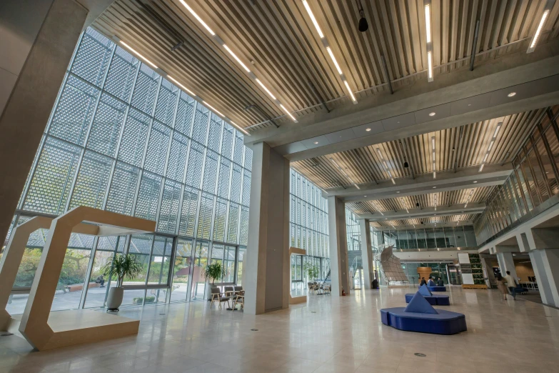 the large lobby of an office building has unique glass walls and wood columns