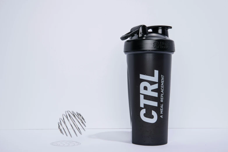 a black protein shaker sits next to a small metal shaker