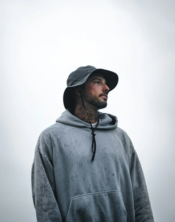 a man is standing with a hat and hoodie