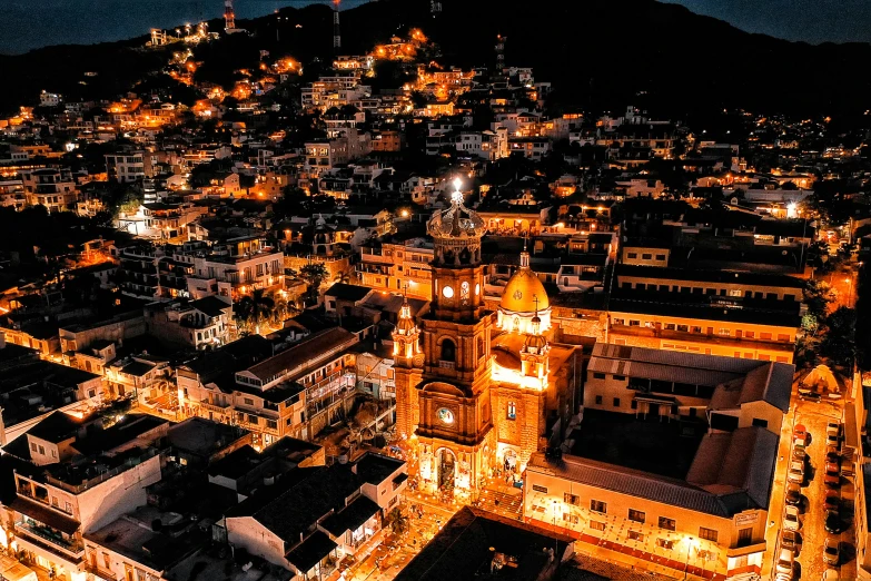 the top view of city with illuminated buildings on a hill at night
