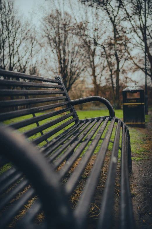 an empty park bench in front of trees