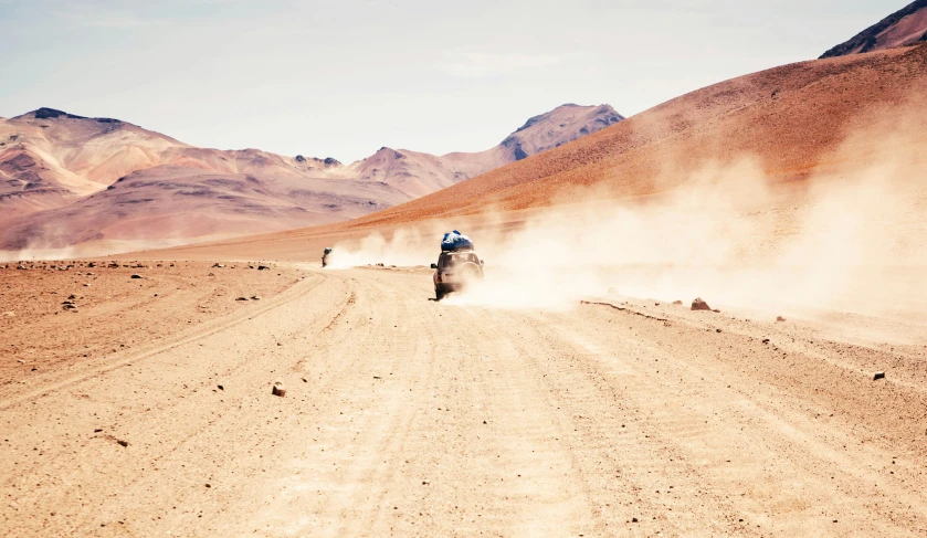 two people ride motorcycles in the desert