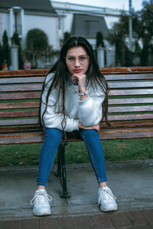 a girl sits on a wooden bench and ponders