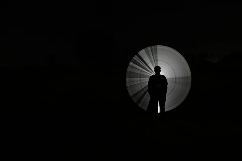 the person stands next to the object on a dark surface