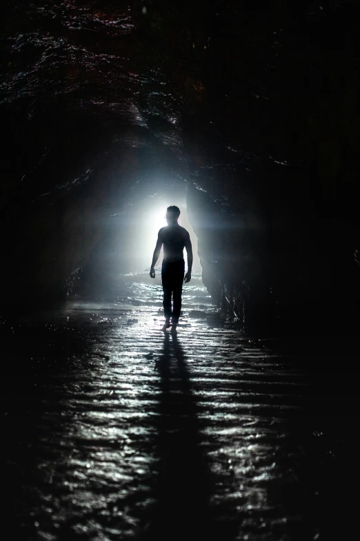 a man walking out of a tunnel into dark