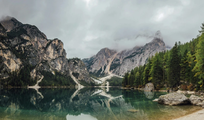 beautiful mountain scene with blue water in foreground and green trees in background