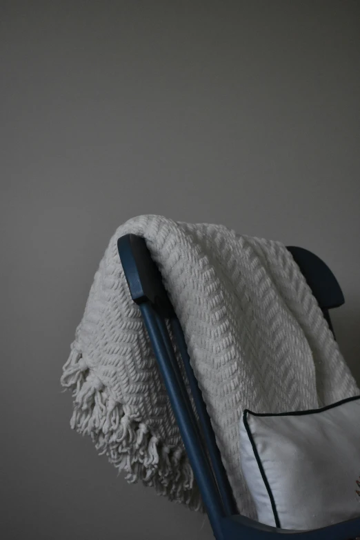 a chair with a cushion and white blanket on it
