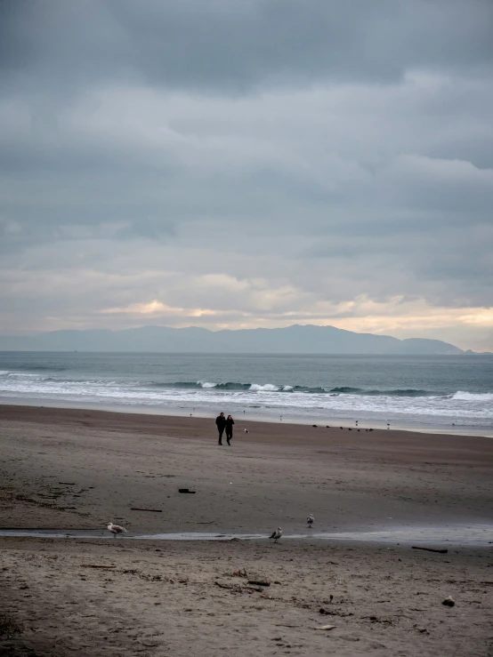 two people on the beach with the ocean in the background