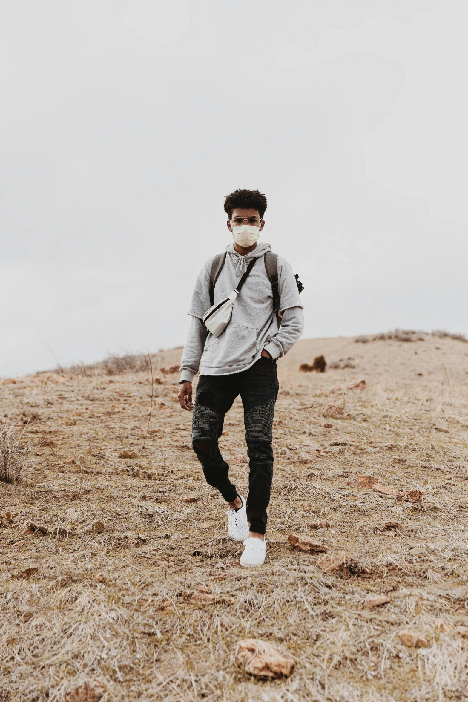 man wearing grey sweatshirt and black skinny pants standing in field