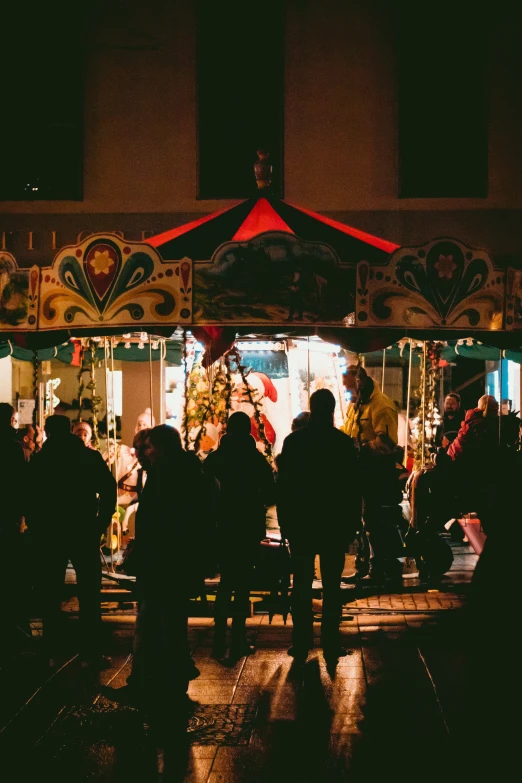 group of people standing in front of fairground booths at night