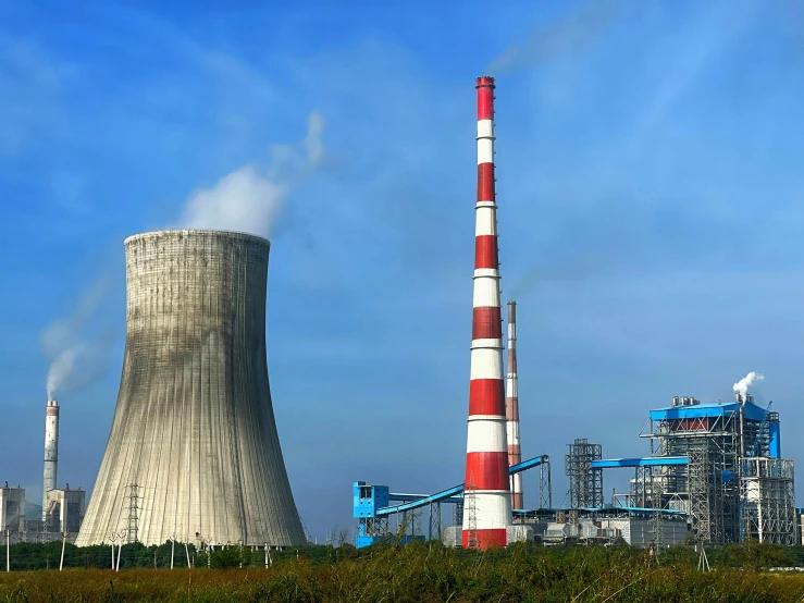 smoke stacks up behind power stations next to an industrial complex